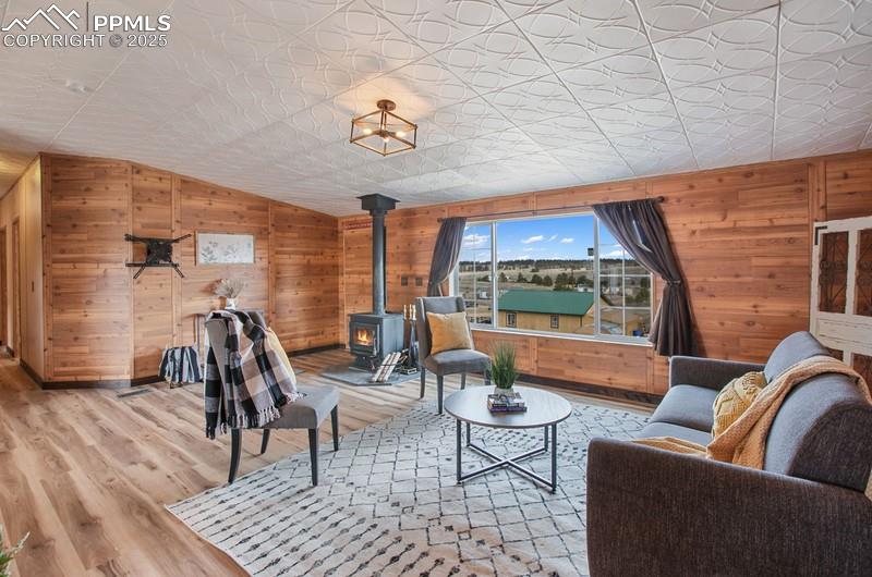 Living area with wood walls, a wood stove, wood finished floors, and lofted ceiling