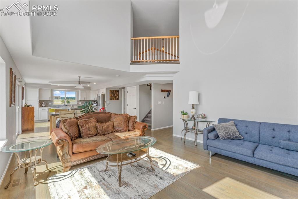 Living area with wood finished floors, a high ceiling, and a ceiling fan
