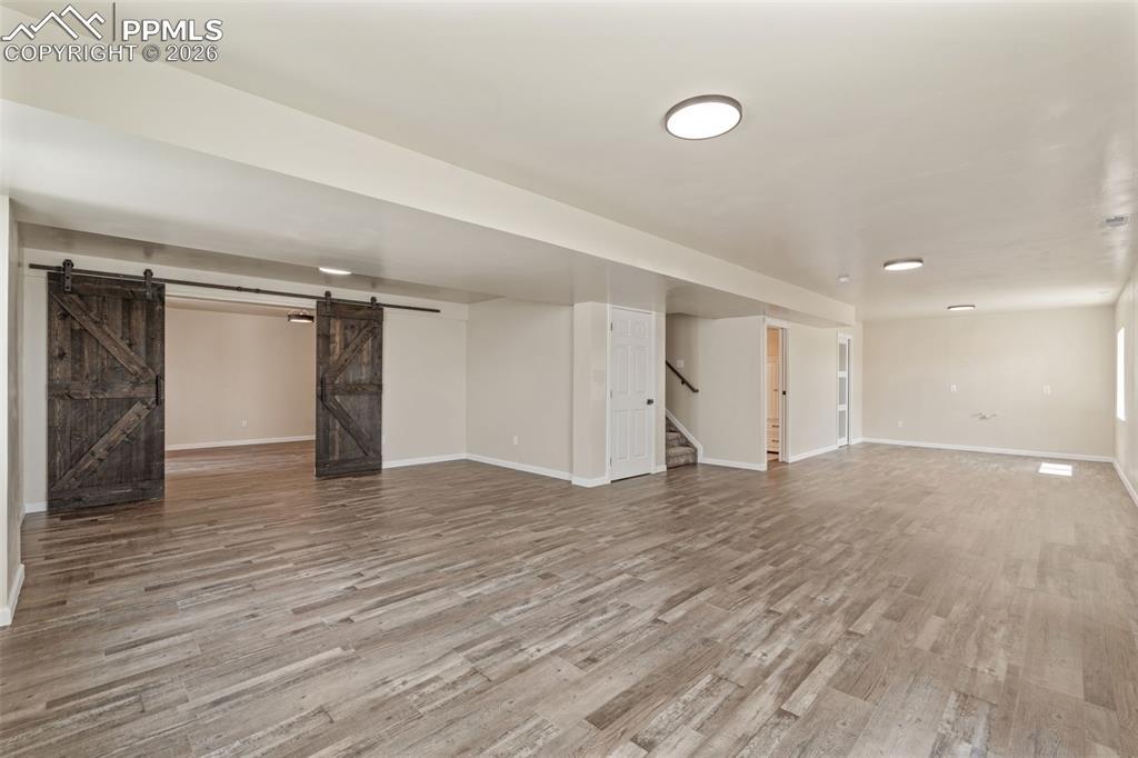 Finished basement featuring a barn door and light wood-type flooring