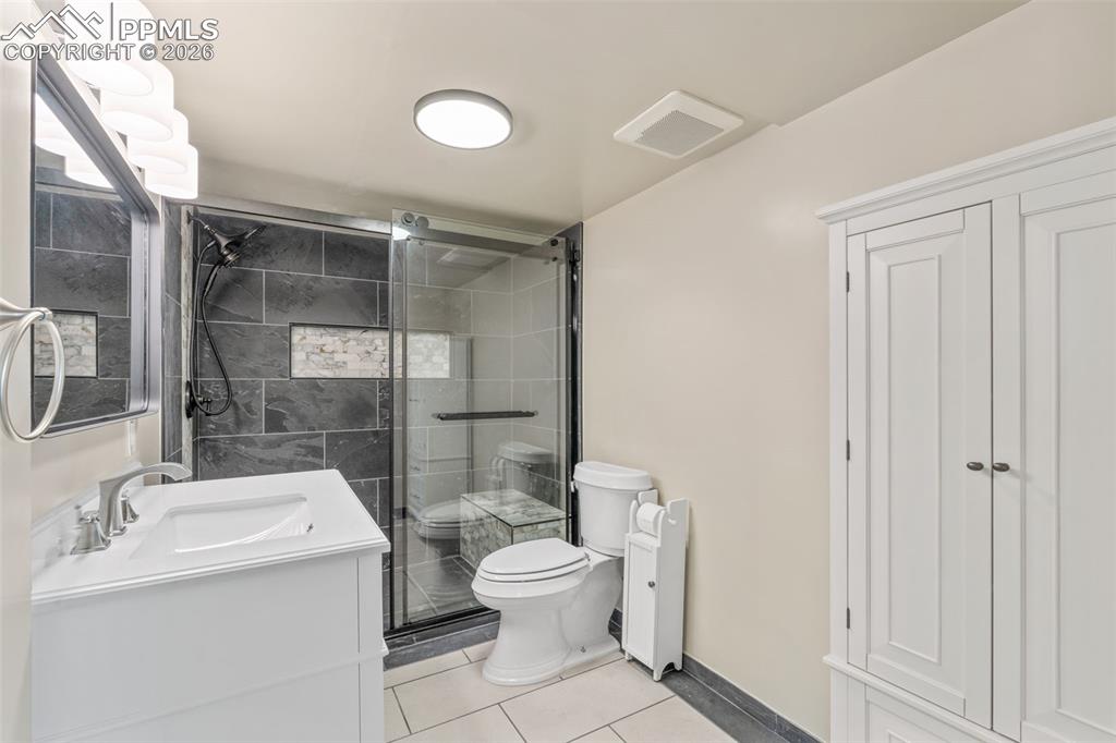 Full bath featuring a shower stall, vanity, and light tile patterned floors