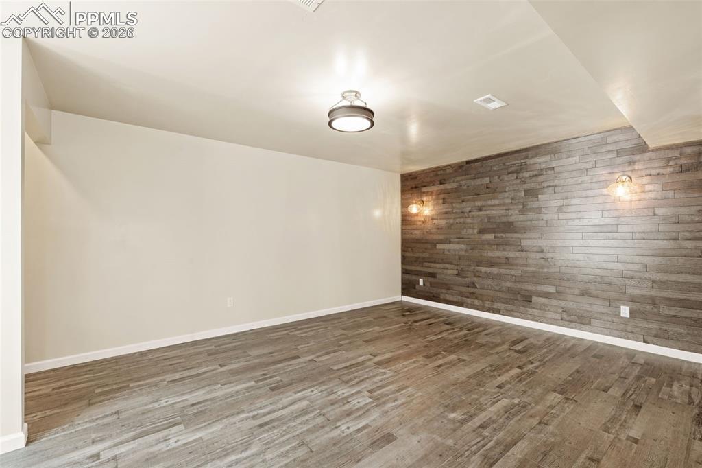 Unfurnished room with wood walls and light wood-style flooring