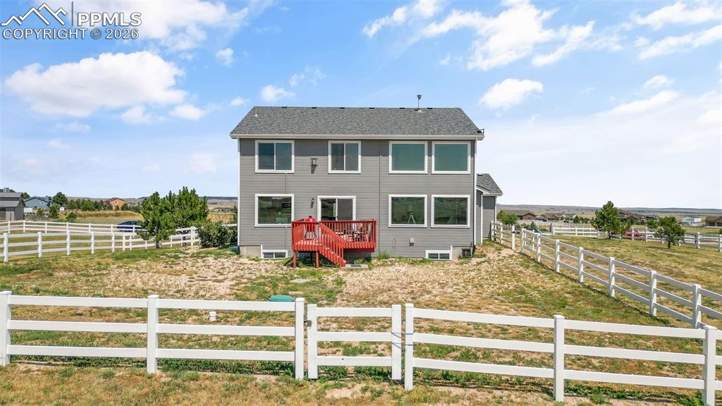 Rear view of house with a fenced backyard, a view of rural / pastoral area, and a wooden deck