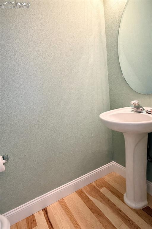 Main-level Power Bathroom with light wood finished floors and pedestal sink