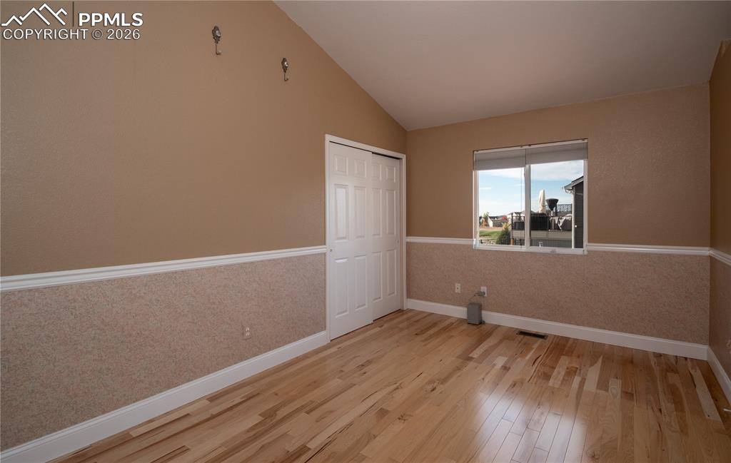 Main-level Bedroom featuring wood finished floors and vaulted ceiling