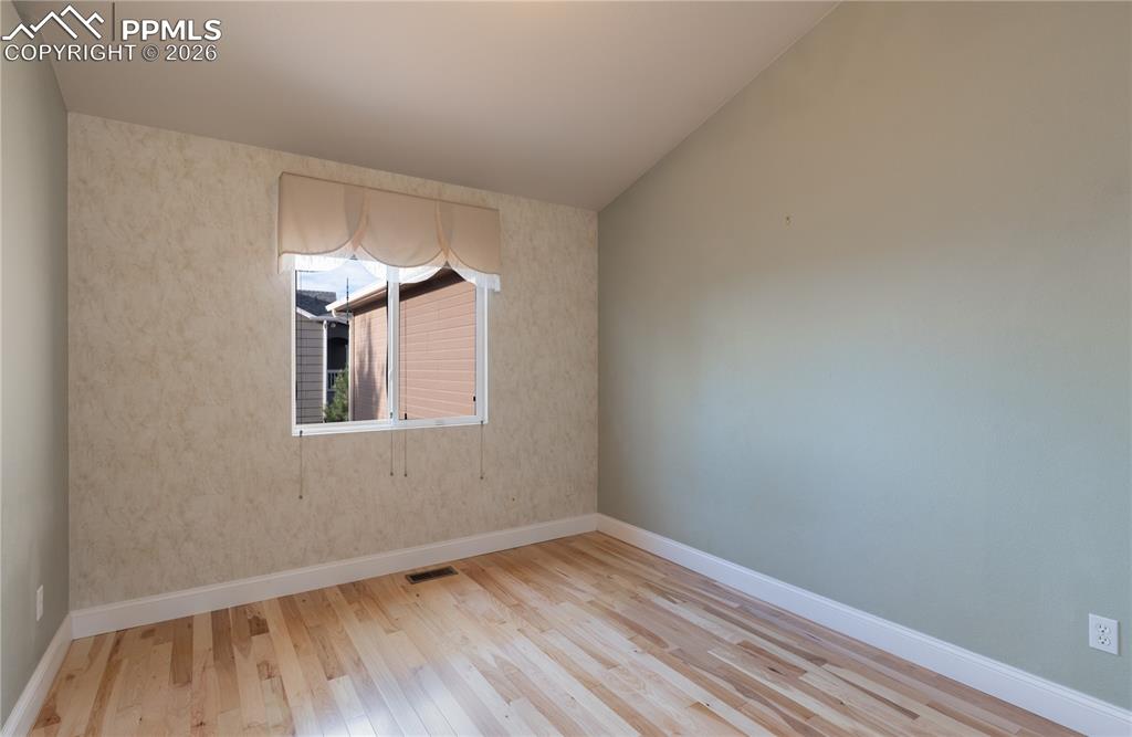 Main-level Bedroom featuring wood finished floors and vaulted ceiling