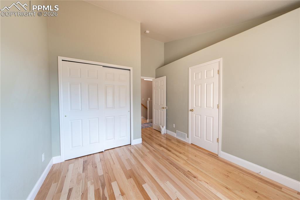 Main-level Bedroom featuring wood finished floors and vaulted ceiling