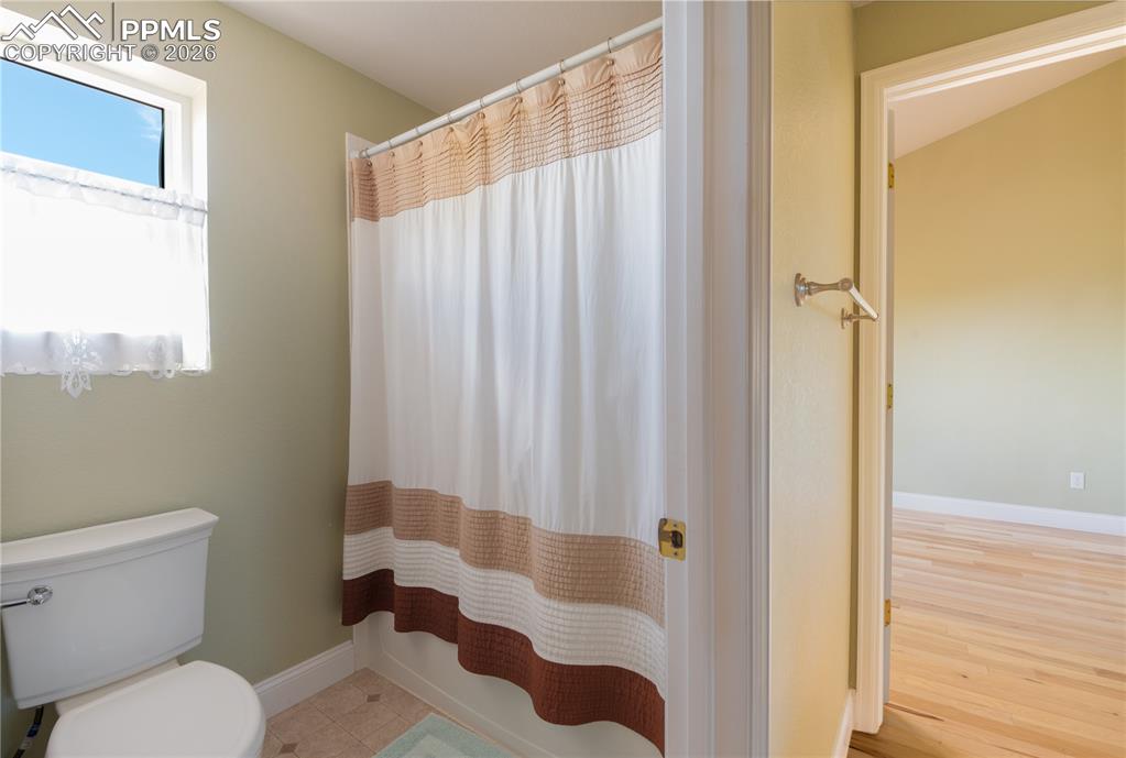 "Jack-and-Jill" Main-level Full Bathroom featuring a double vanity and light wood finished floors, enclosed entrance to water closet/shower/tub combo