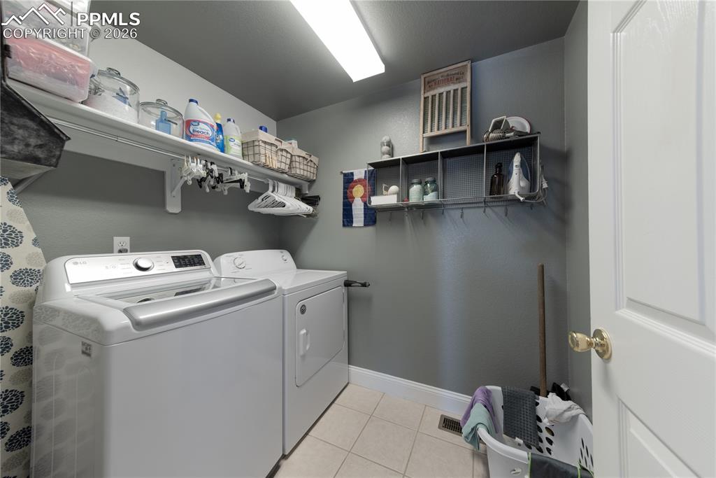 Main-level Laundry area with washer and dryer and light tile patterned floors