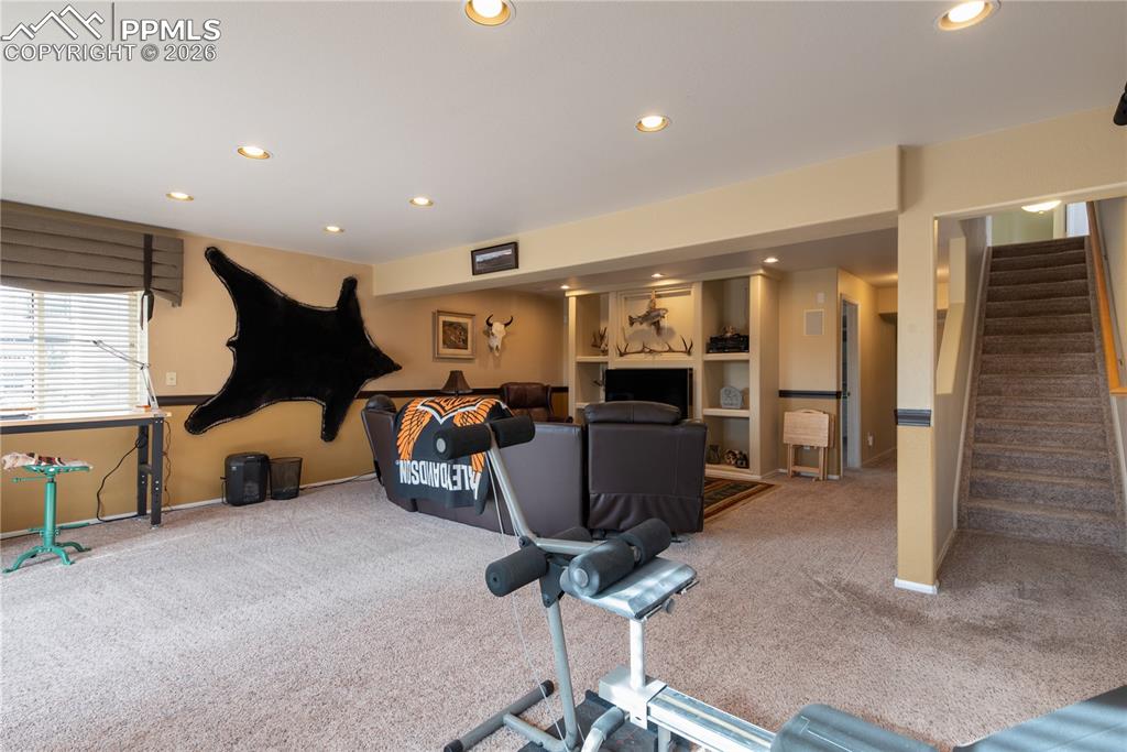 Living/Family/Den room featuring carpet floors and recessed lighting, built-in shelving for entertainment audio/video equipment, walkout basement, with garden-level windows allowing for superior outdoor lighting