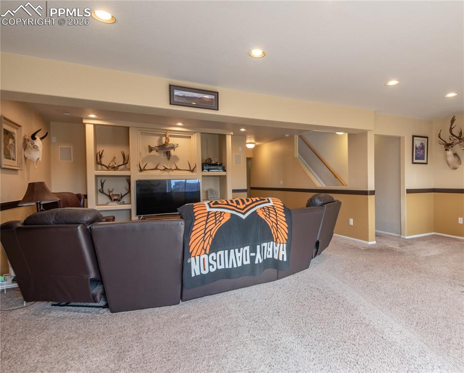 Living/Family/Den room featuring carpet floors and recessed lighting, built-in shelving for entertainment audio/video equipment, walkout basement, with garden-level windows allowing for superior outdoor lighting