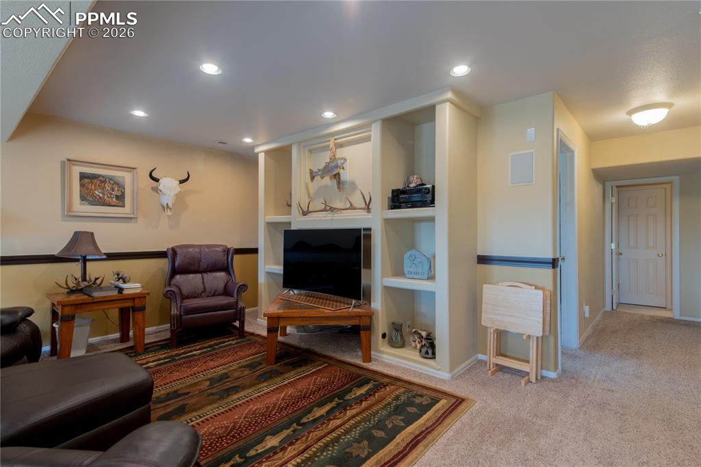 Living/Family/Den room featuring carpet floors and recessed lighting, built-in shelving for entertainment audio/video equipment, walkout basement, with garden-level windows allowing for superior outdoor lighting