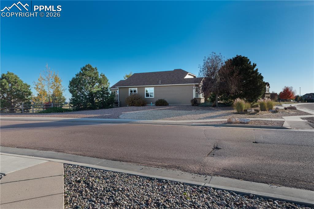 North View of Ranch-style home with fully manicured front yard, driveway, and a 4-car garage on a corner lot of house with concrete driveway, a 4-car garage with brick and masonite-type siding