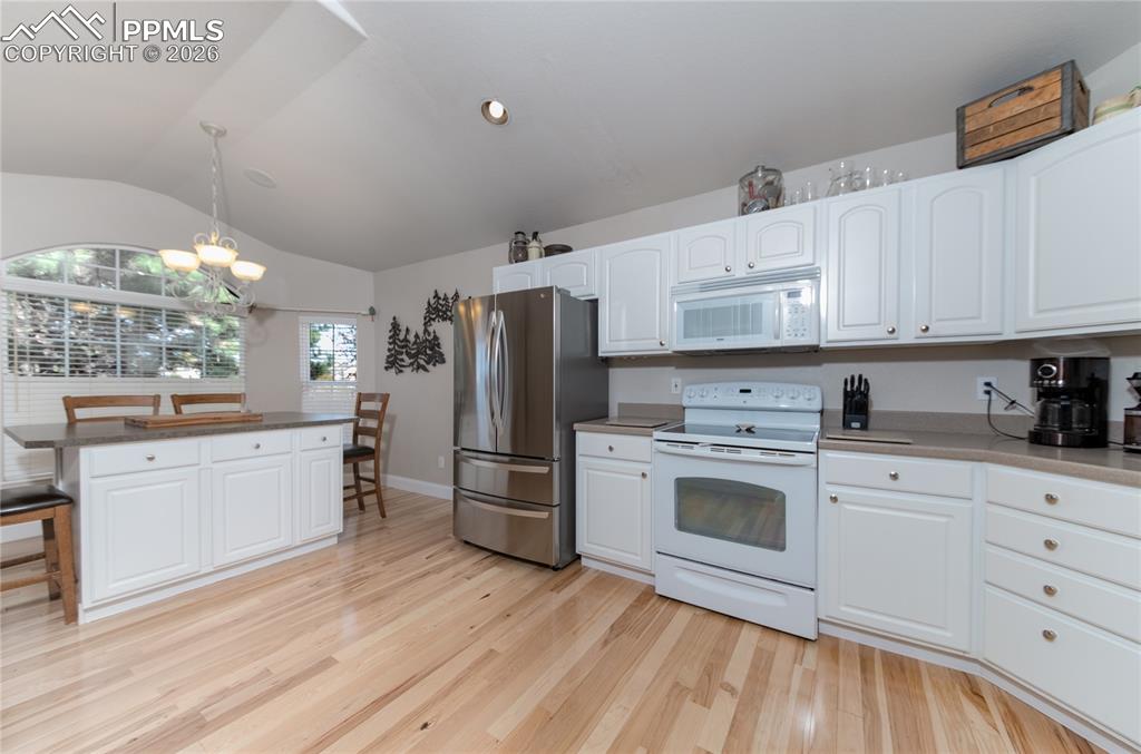 Kitchen with white cabinetry, light wood-type flooring, dishwasher, and light solid-state countertops