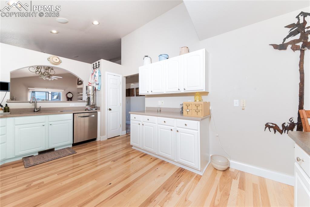 Kitchen with white cabinetry, light wood-type flooring, dishwasher, and light solid-state countertops