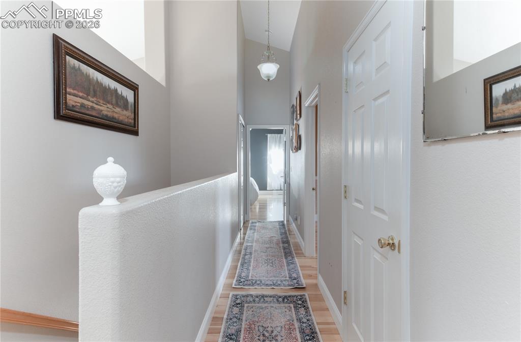 Looking to Primary Bedroom - Hallway featuring high vaulted ceiling and light wood-style floors