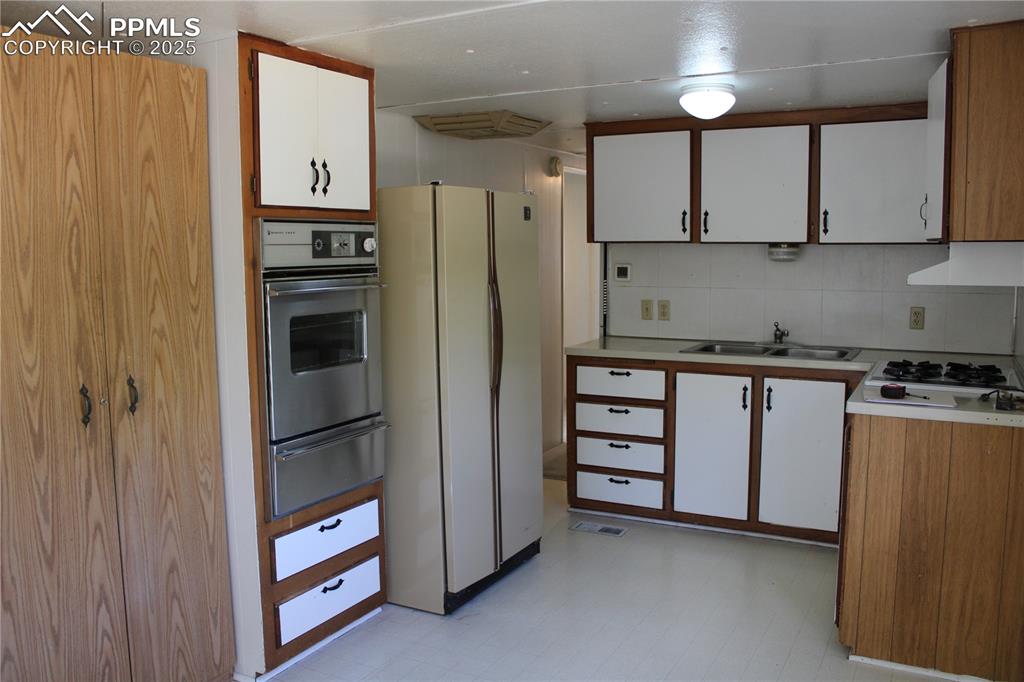 Kitchen featuring white cabinetry, light flooring, light countertops, white appliances, and decorative backsplash