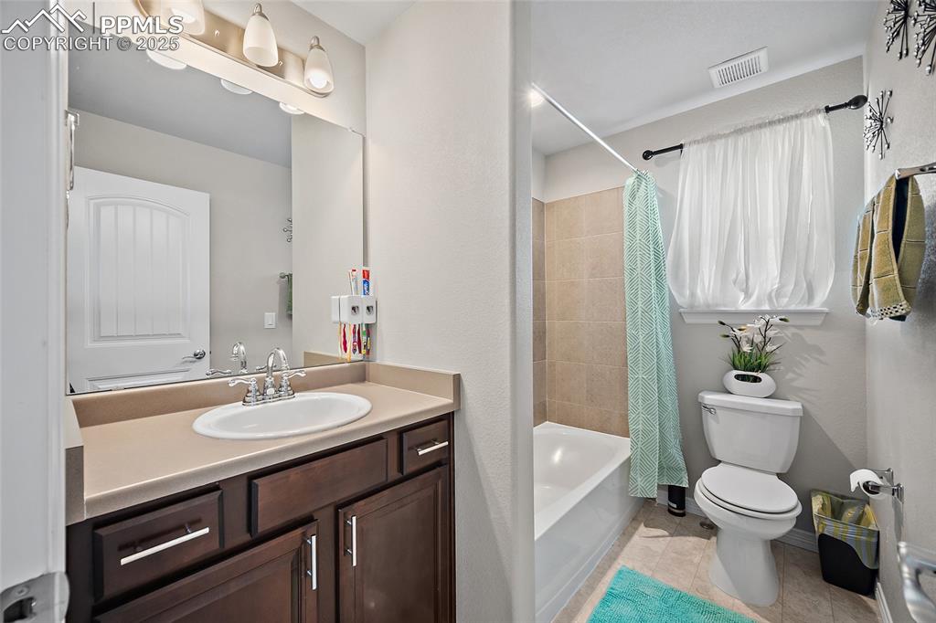 Bathroom with vanity, shower / tub combo with curtain, and light tile patterned flooring