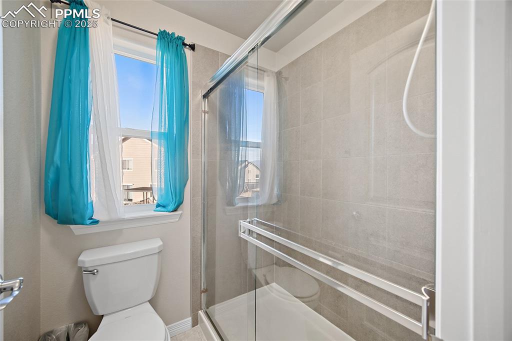 Full bathroom featuring toilet and a shower stall