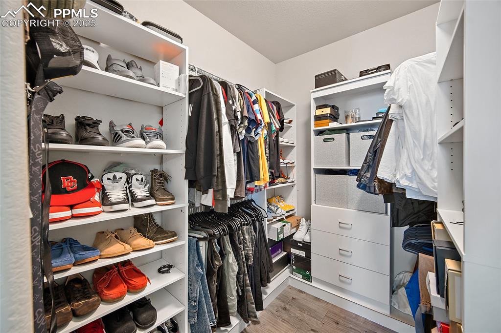 Walk in closet with light wood-style flooring