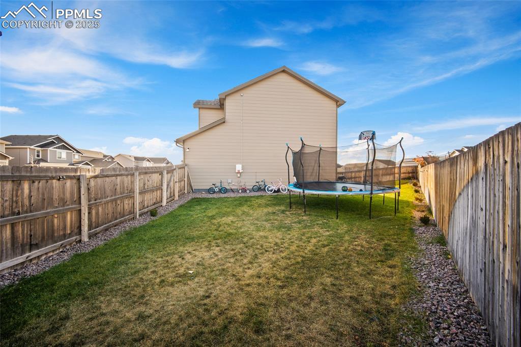 Back of house featuring a fenced backyard and a trampoline