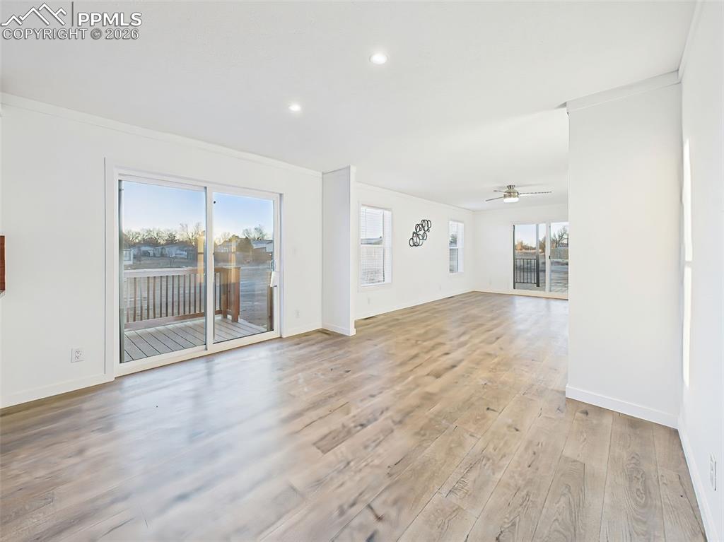 This bright, open-concept kitchen and dining space features crisp white cabinetry, stainless steel appliances, and a center island with bar seating. A sliding glass door leads directly to the back deck, perfect for indoor-outdoor dining.