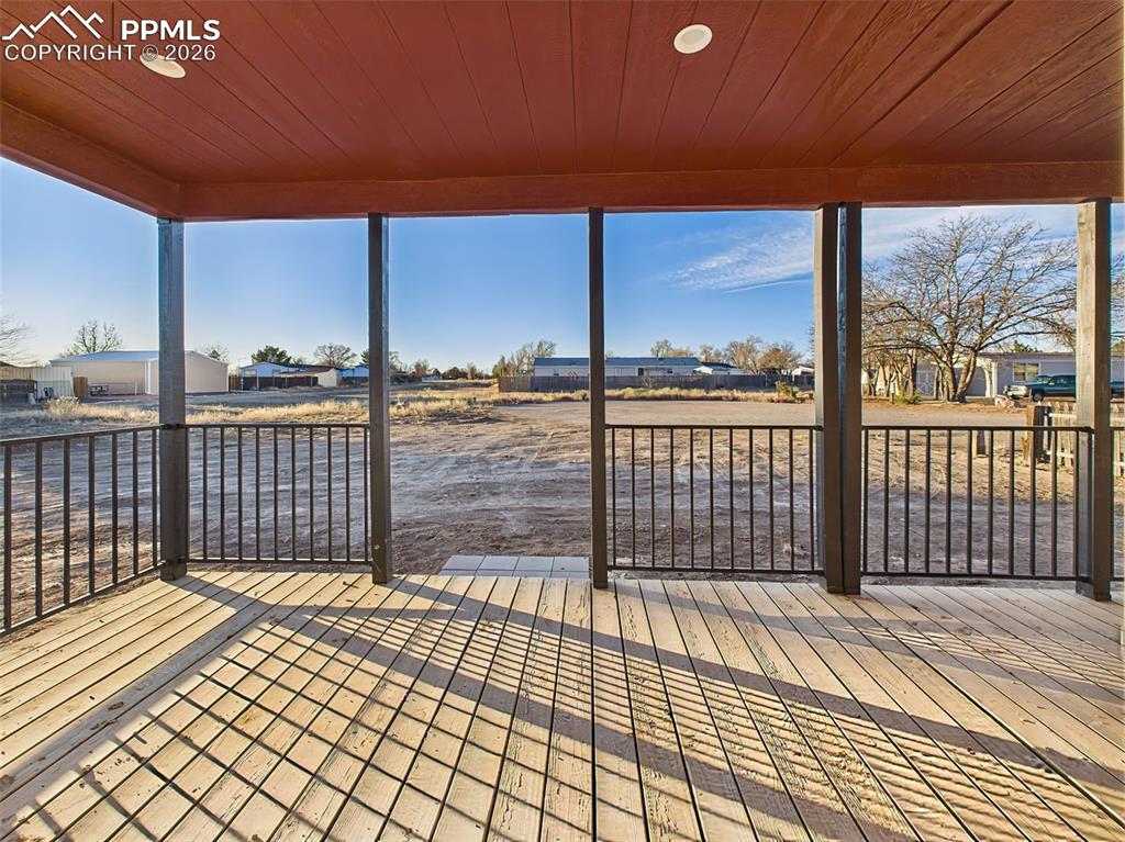Unfurnished view of the covered back patio, offering open sightlines to the expansive lot and surrounding neighborhood.