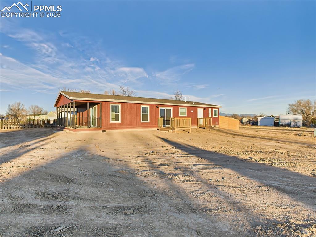 A full side view of the home’s rear showcases the red siding, two outdoor decks, and generous lot size with endless potential.