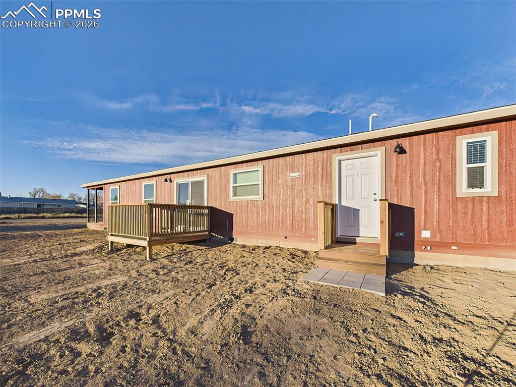 The rear of the home includes a simple back entry with steps and a modest landing, overlooking a wide open lot ready for personalization.