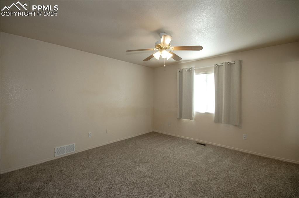 Primary or Master bedroom featuring new carpet flooring and ceiling fan
