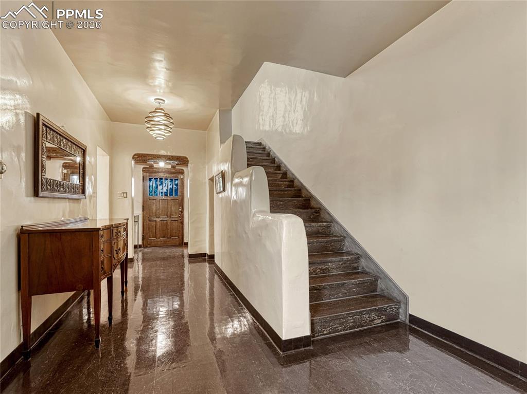 Entry to home with stepped parapet stairwell wall and art deco linoleum flooring.