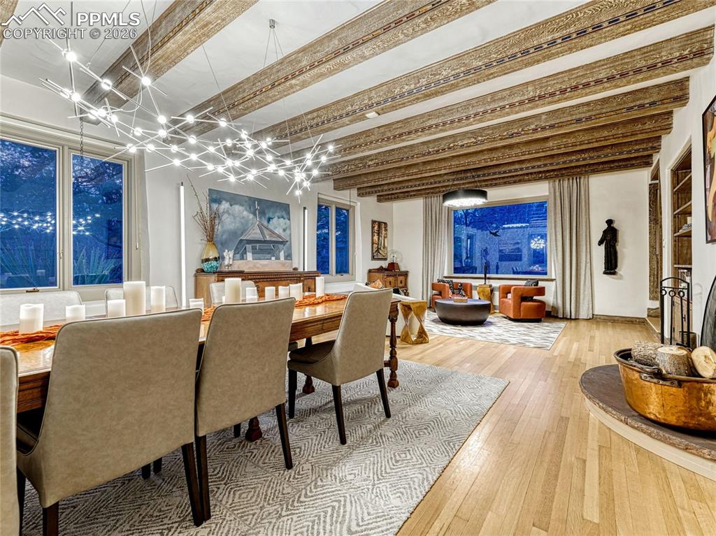 Grand living/dining with original hardwood flooring, wood-burning fireplace, hand-carved and painted beamed ceiling.