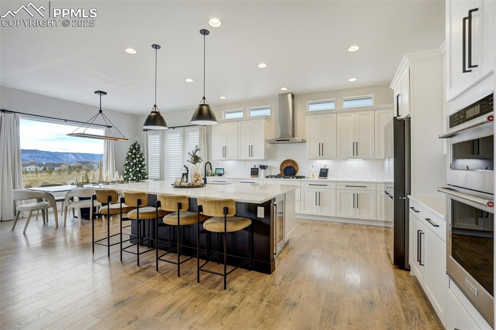 Gourmet kitchen with upgraded appliances, quartz counters, beverage fridge, upgraded cabinetry, massive island, spacious pantry, gas cooktop, and built in microwave/airfryer