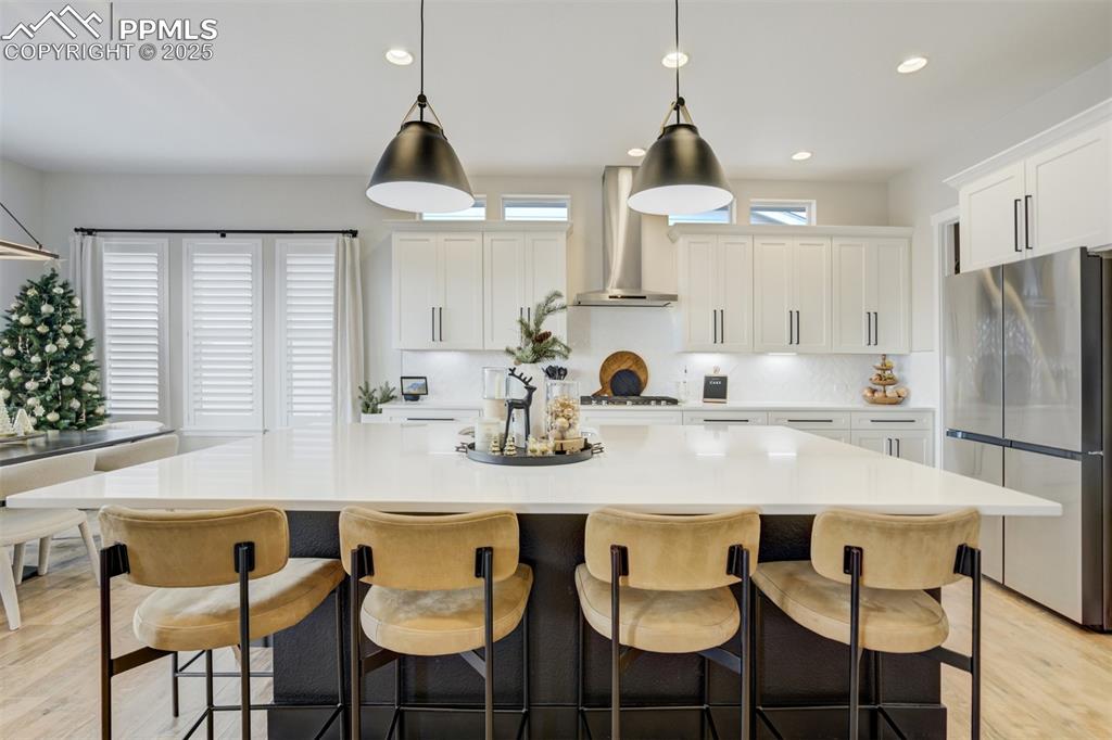 Gourmet kitchen with upgraded appliances, quartz counters, beverage fridge, upgraded cabinetry, massive island, spacious pantry, gas cooktop, and built in microwave/airfryer