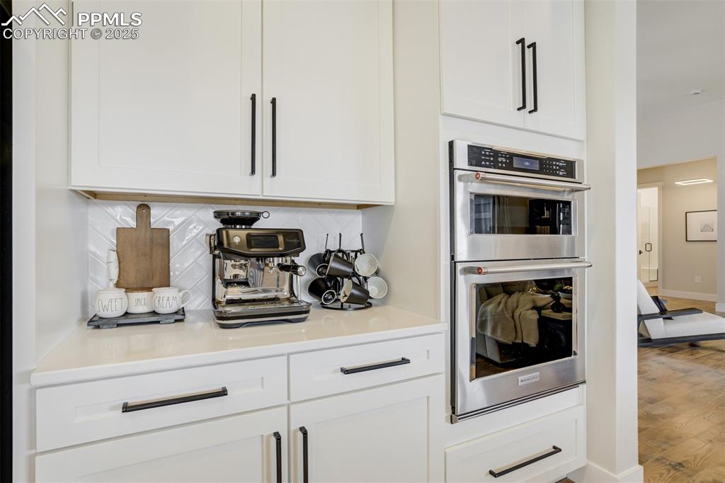 Gourmet kitchen with upgraded appliances, quartz counters, beverage fridge, upgraded cabinetry, massive island, spacious pantry, gas cooktop, and built in microwave/airfryer