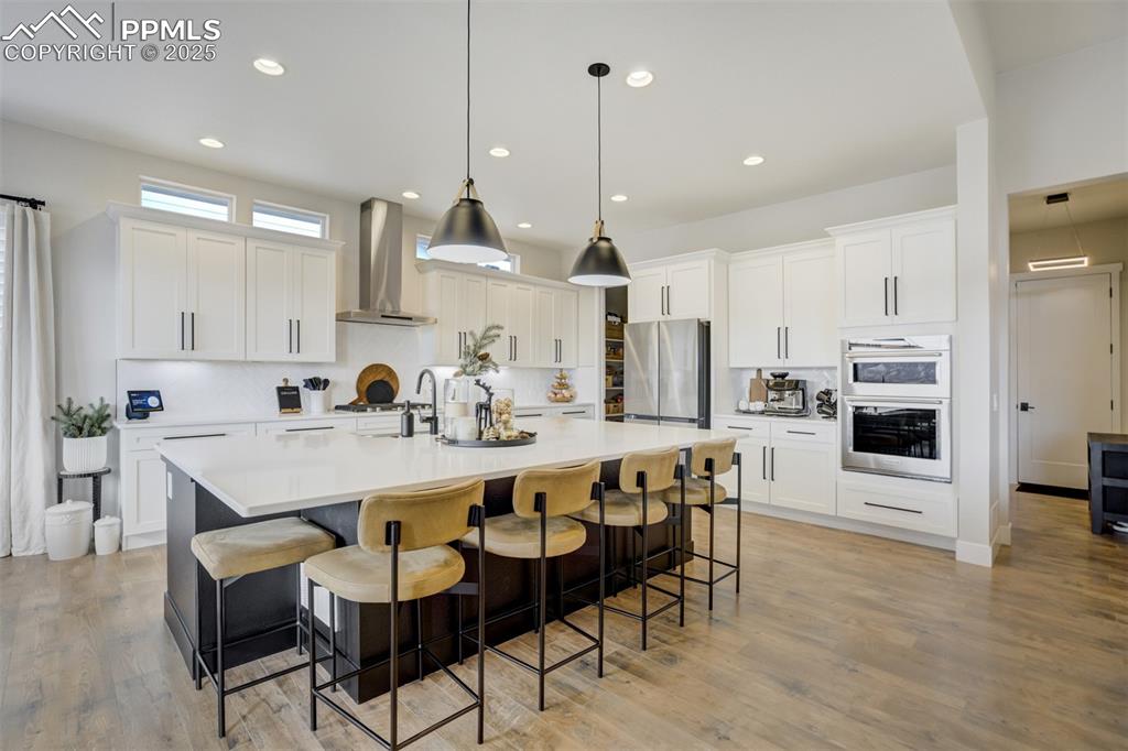 Gourmet kitchen with upgraded appliances, quartz counters, beverage fridge, upgraded cabinetry, massive island, spacious pantry, gas cooktop, and built in microwave/airfryer