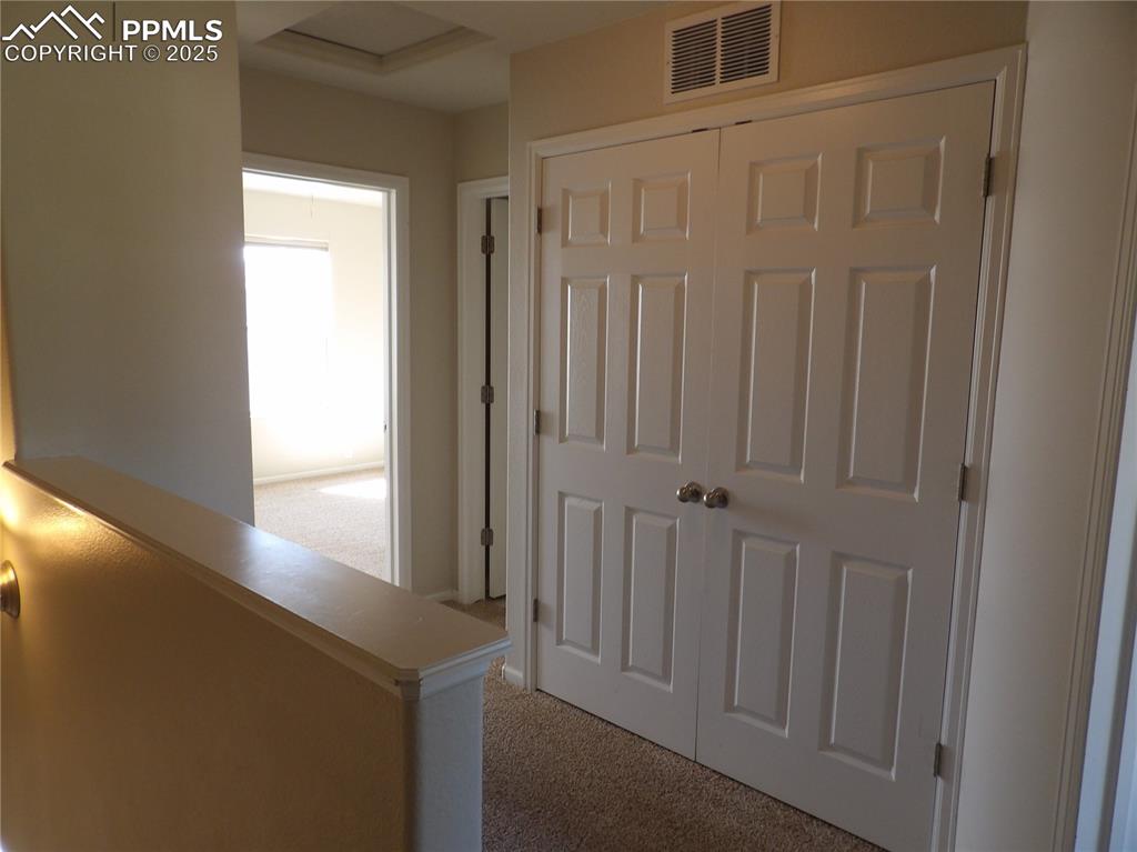 Hallway featuring light carpet