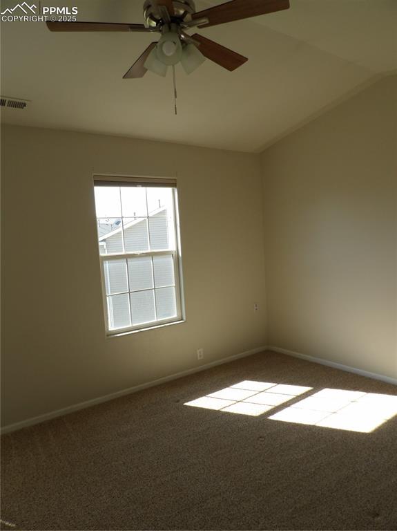 Carpeted spare room with a ceiling fan and lofted ceiling