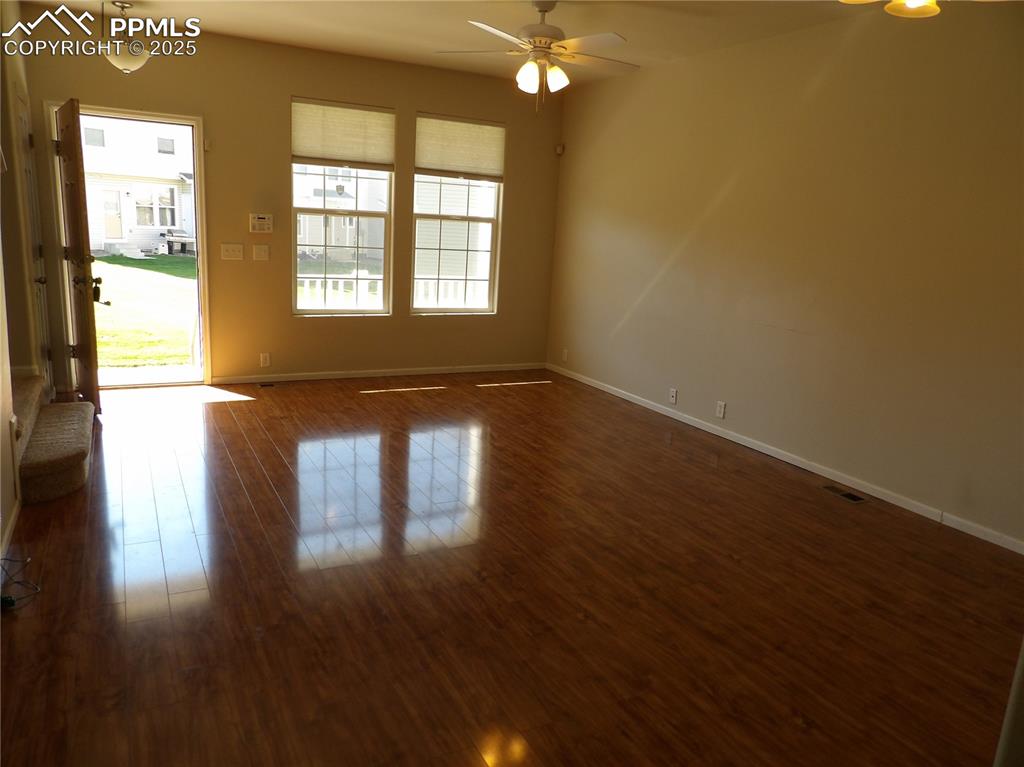 Empty room with dark wood-style flooring and ceiling fan