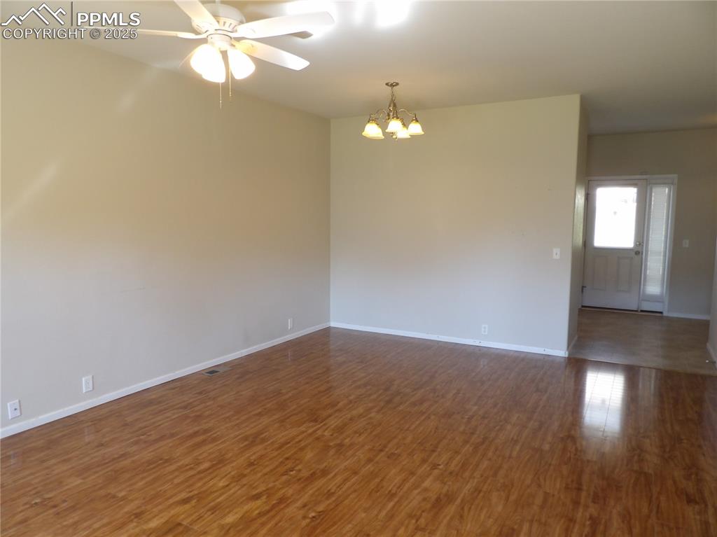 Unfurnished room featuring a chandelier, ceiling fan, and dark wood-style floors
