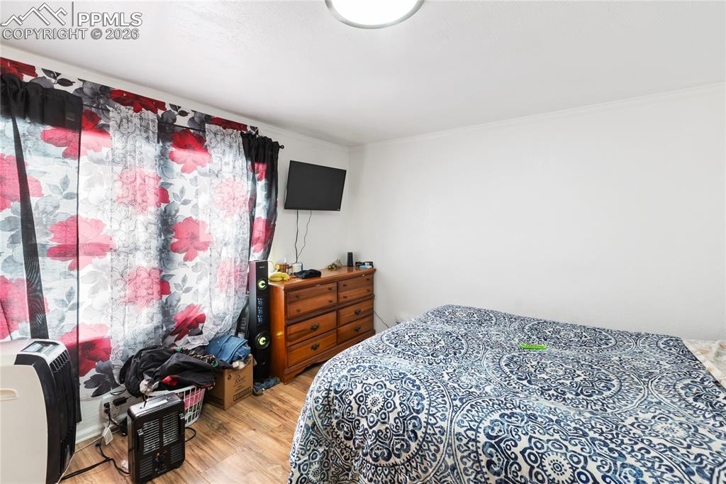 The bedroom featuring wood finished floors and ornamental molding