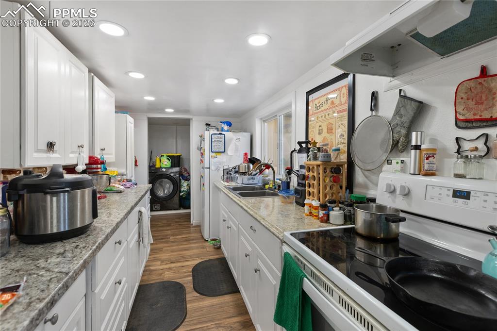 The kitchen has hard wood floors, white appliances, a range hood, and white cabinets!