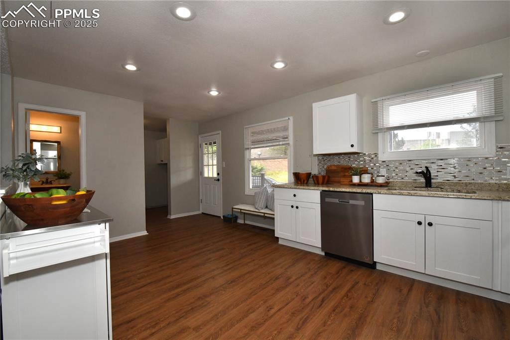 Kitchen with backsplash, stainless steel dishwasher, white cabinets, dark wood-style floors, and recessed lighting