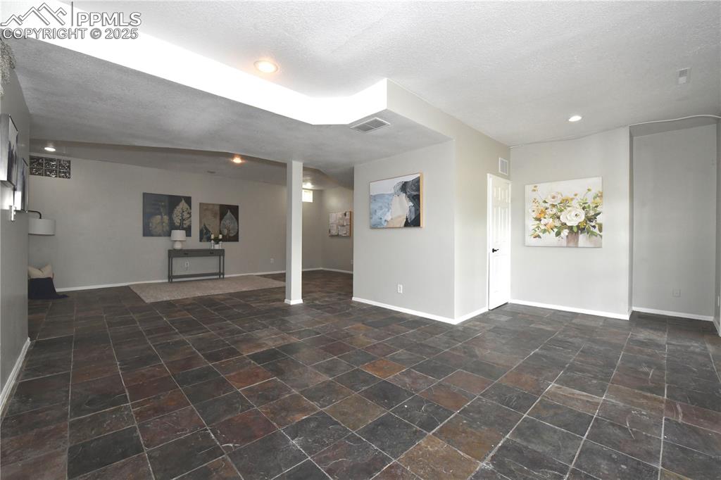 Unfurnished living room featuring recessed lighting, stone finish flooring, and a textured ceiling