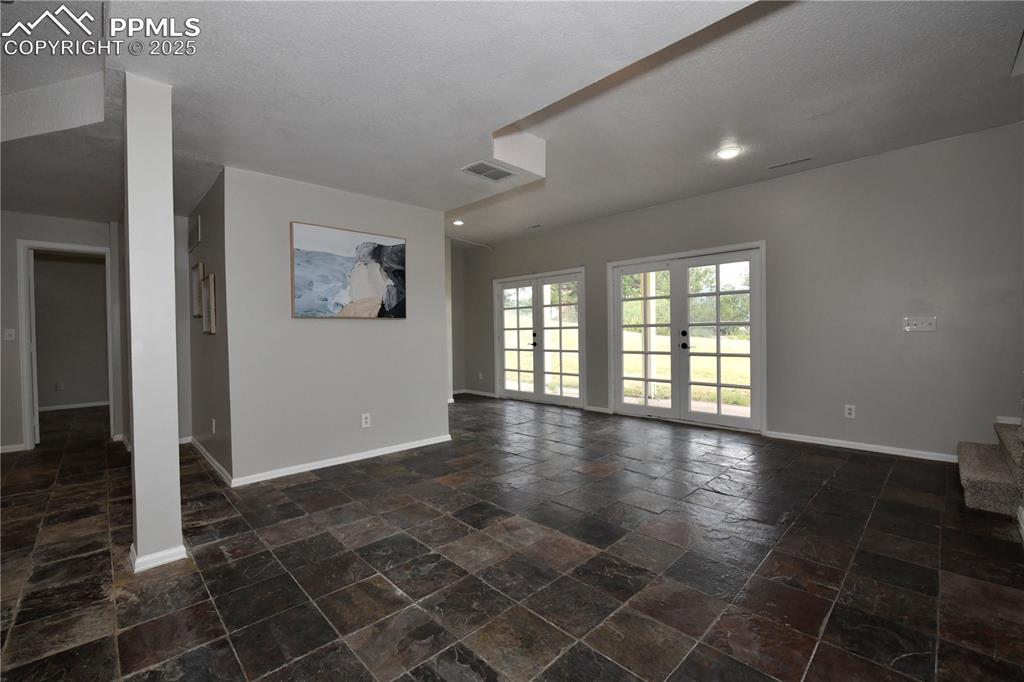 Unfurnished living room featuring baseboards and stone tile floors