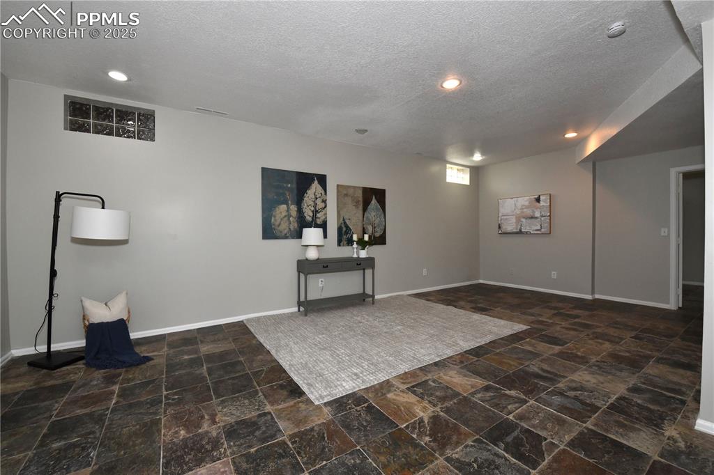 Basement with stone finish flooring, a textured ceiling, and recessed lighting