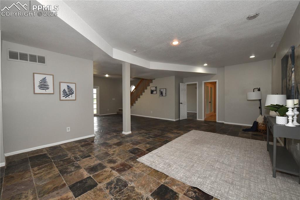 Below grade area with stone finish floors, stairway, and a textured ceiling