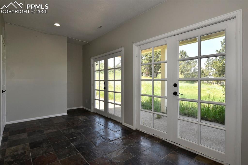 Doorway with baseboards, plenty of natural light, stone tile floors, french doors, and recessed lighting
