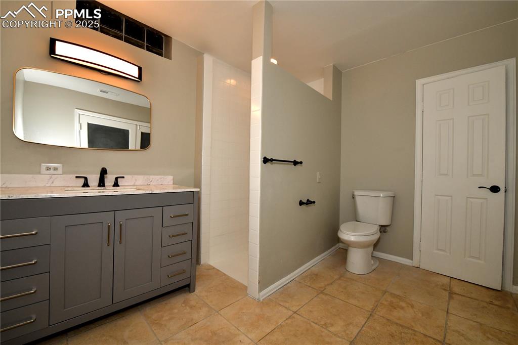 Bathroom featuring vanity, toilet, tile patterned flooring, and tiled shower