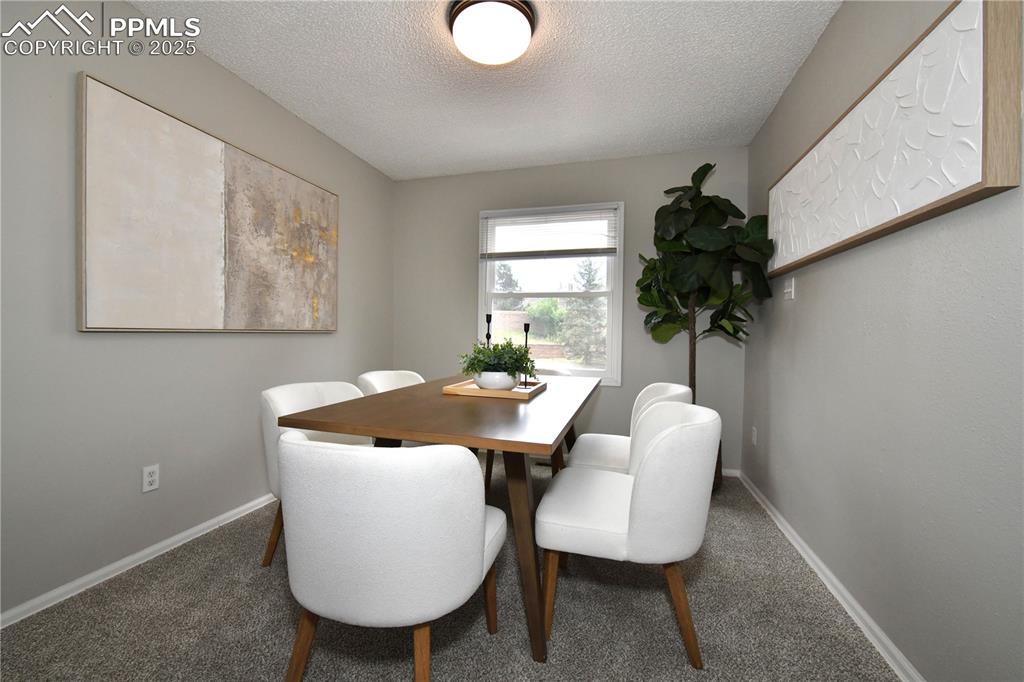 Carpeted dining space with a textured ceiling and baseboards