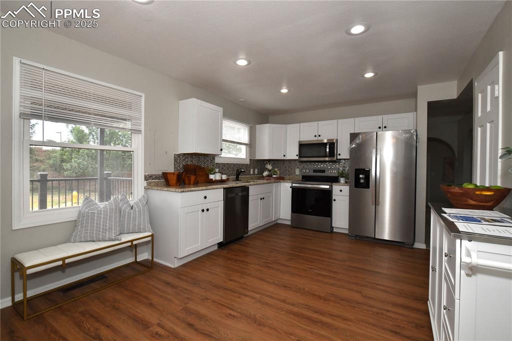 Kitchen featuring stainless steel appliances, white cabinetry, dark wood-style floors, backsplash, and recessed lighting